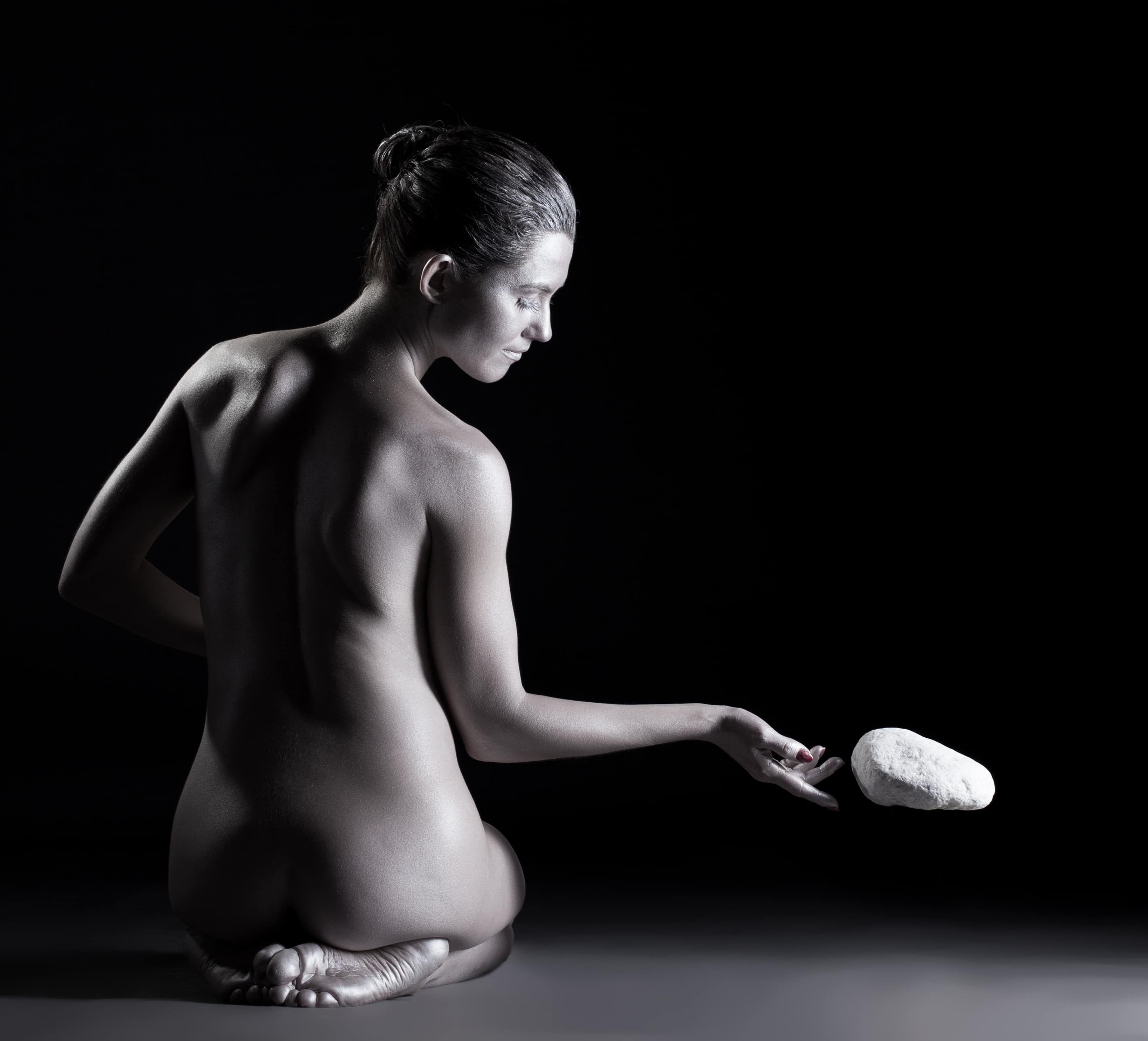 Spiritual nude woman telekinetically moving stone