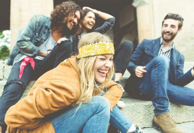 Group of four friends laughing out loud outdoor sharing good and positive mood