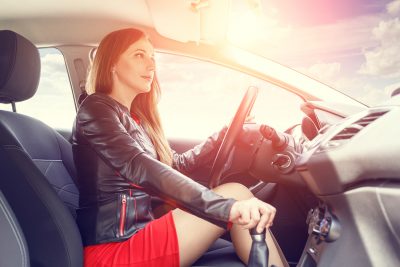 Young woman driving a car. Fast delivery or taxi concept background